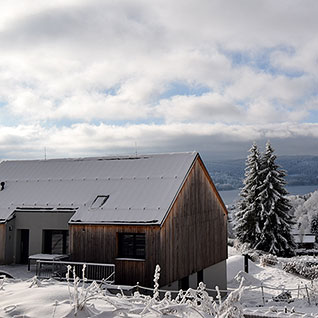 Pohled na zasněžený apartmánový dům Green Stone a Lipno